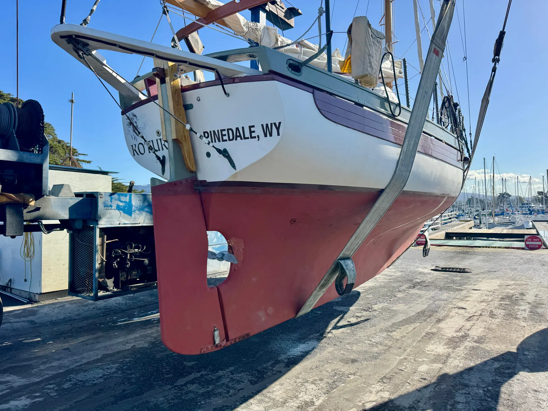 1982 Bristol Channel Cutter 28 sailboat lifted at a marina, showing red hull and white deck.