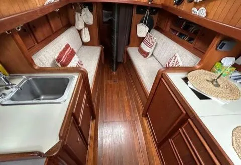 Interior of 1982 Bristol Channel Cutter 28, featuring cozy seating and wooden cabinetry.