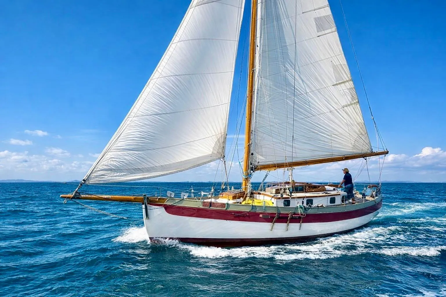Sailing a 1982 Bristol Channel Cutter 28 on open sea under clear blue skies.