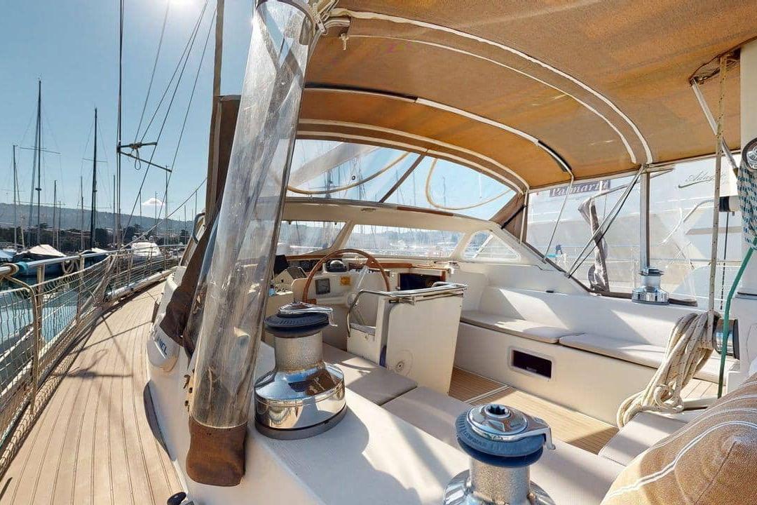 Amel Super Maramu 2000 sailboat cockpit, 2001 model, with sunshade and marina view.