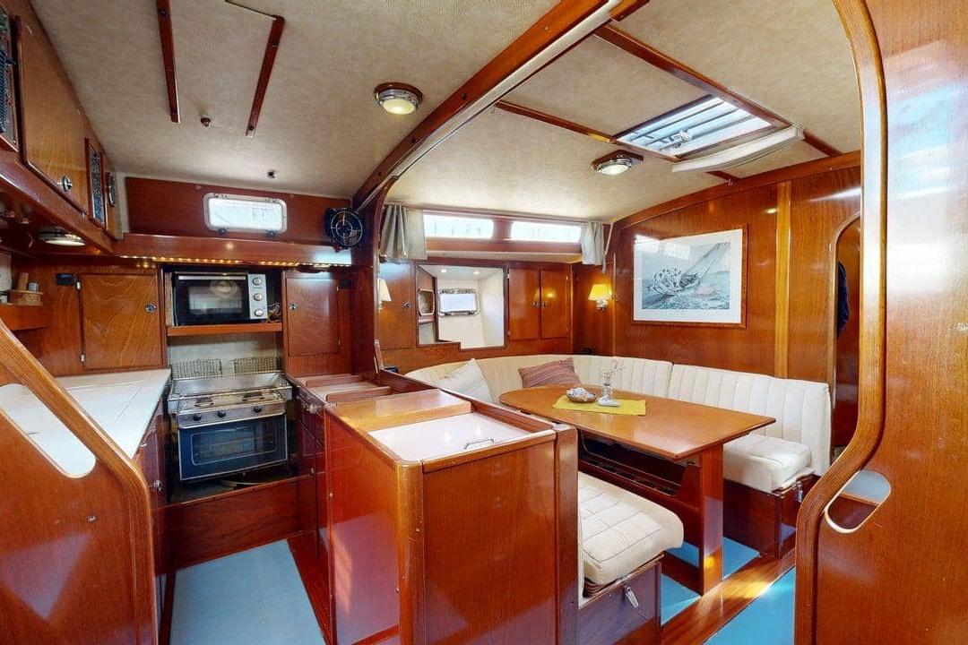 Luxurious interior of 2001 Amel Super Maramu 2000 yacht with wood finish and dining area.