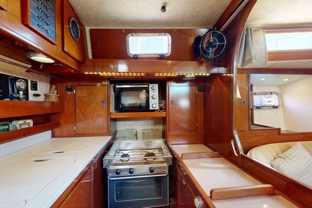 Luxurious 2001 Amel Super Maramu 2000 yacht kitchen with wood cabinetry and modern appliances.