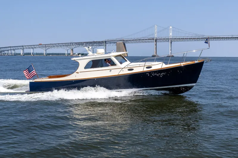 Sometimes Yacht Photos Pics 2007 Hinckley Picnic Boat EP cruising on water near a bridge, American flag displayed.