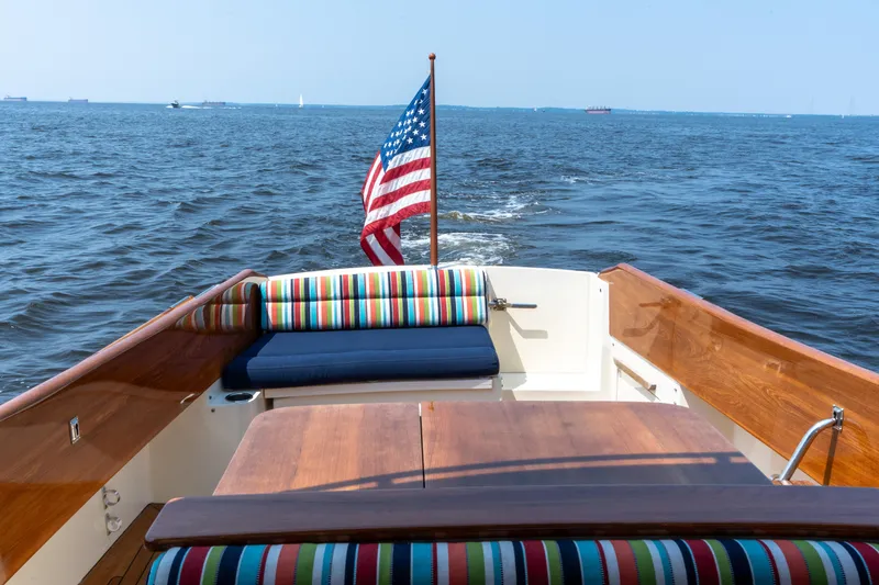 Sometimes Yacht Photos Pics 2007 Hinckley Picnic Boat EP cruising with American flag, colorful seating, and wooden deck.