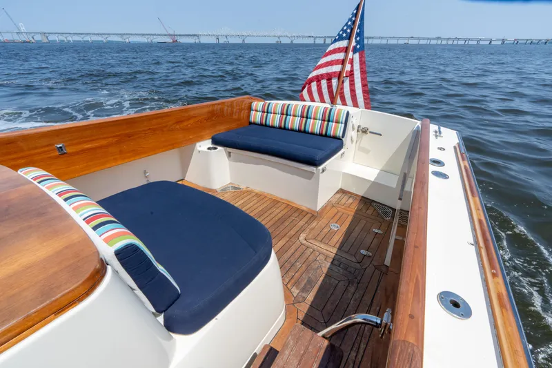Sometimes Yacht Photos Pics 2007 Hinckley Picnic Boat EP with American flag, wooden deck, and colorful seating on the water.