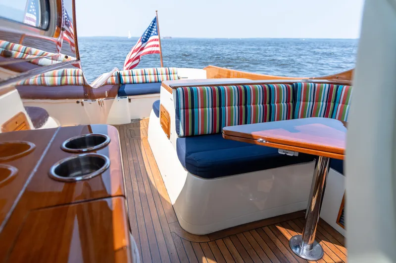 Sometimes Yacht Photos Pics 2007 Hinckley Picnic Boat EP interior with striped seating, wooden table, and ocean view.