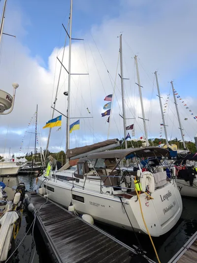 Leopolis Yacht Photos Pics 2019 Jeanneau Sun Odyssey 440 Performance yacht docked, surrounded by flags and other boats.