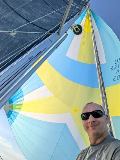 Leopolis Yacht Photos Pics Man sailing on Jeanneau Sun Odyssey 440 with colorful spinnaker sail.