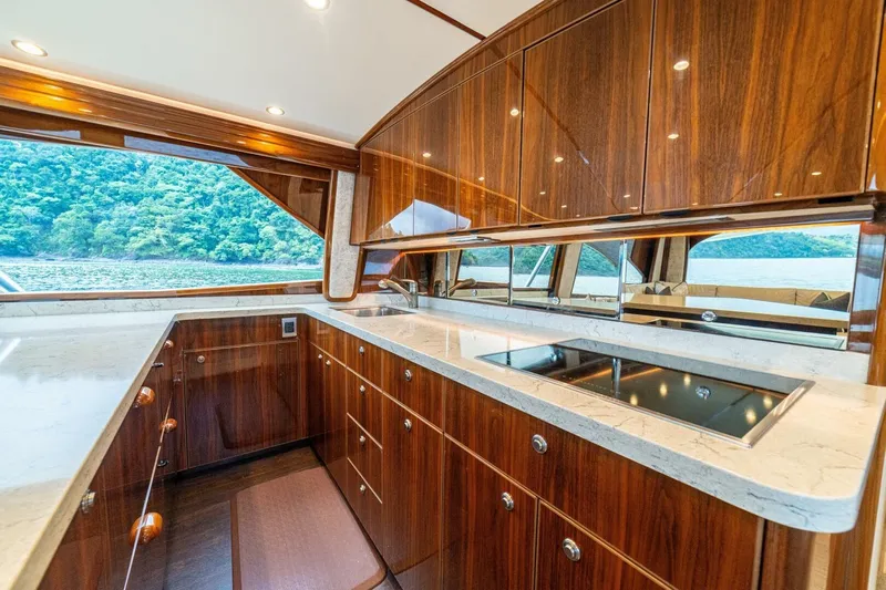 Galati Yacht Sales Trade Yacht Photos Pics Luxurious kitchen interior of 2021 Viking 58 Convertible yacht with wood cabinetry and scenic view.