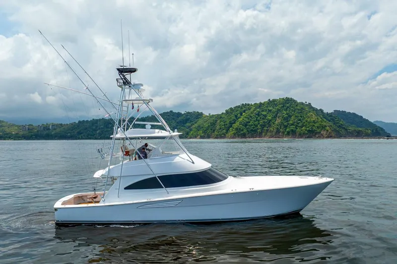 Galati Yacht Sales Trade Yacht Photos Pics 2021 Viking 58 Convertible yacht cruising near lush green island under cloudy sky.