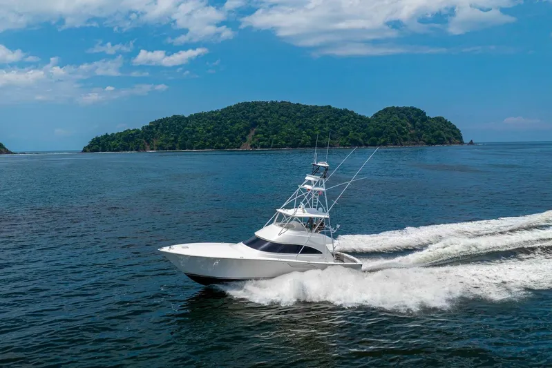 Galati Yacht Sales Trade Yacht Photos Pics 2021 Viking 58 Convertible yacht cruising on open water near lush island.