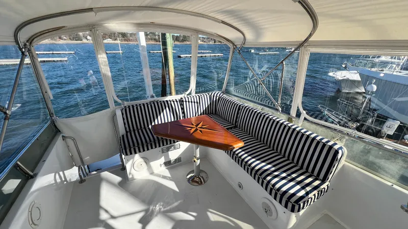 La Vie Dansante Yacht Photos Pics 1998 Little Harbor WhisperJet 55 yacht interior with striped seating and wooden table, overlooking water.