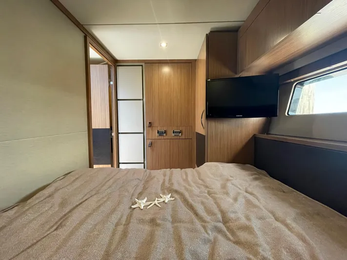 Kings' Ransom Yacht Photos Pics Luxurious 2017 Sea Ray L590 Fly cabin interior with bed, TV, and wooden accents.