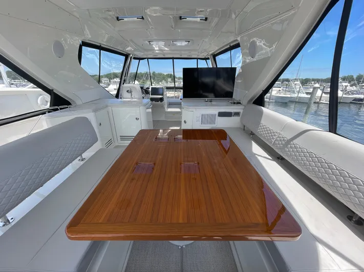 Kings' Ransom Yacht Photos Pics Luxurious interior of 2017 Sea Ray L590 Fly yacht with polished wood table and panoramic windows.