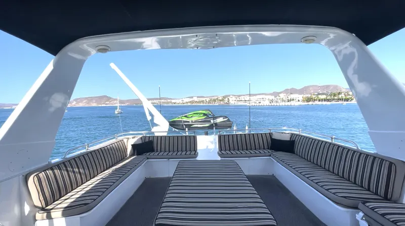Fnfun Yacht Photos Pics 1989 Hatteras CPMY yacht with striped seating, overlooking serene blue waters and distant hills.