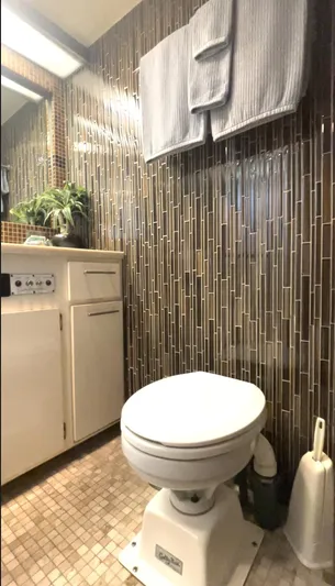Fnfun Yacht Photos Pics 1989 Hatteras CPMY bathroom with modern tile, white toilet, and cabinet.