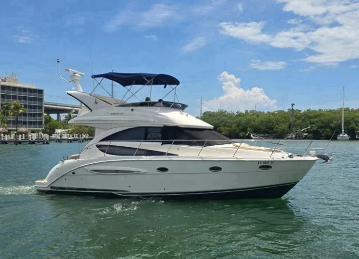  Yacht Photos Pics 2012 Meridian 341 Sedan yacht cruising on a sunny day, surrounded by lush greenery.