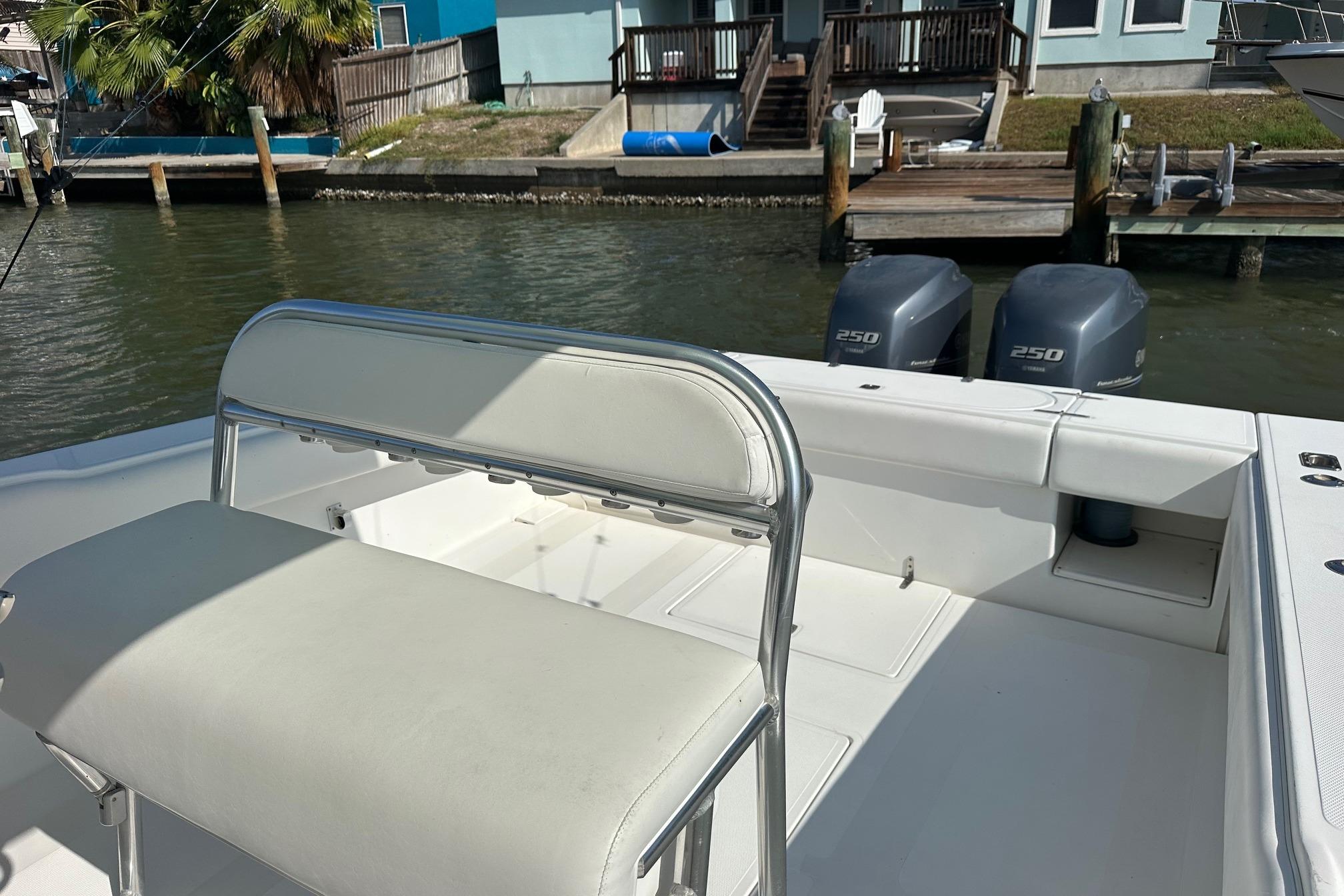 2003 Venture 34 Center Console boat with dual 250 horsepower engines docked by waterfront homes.
