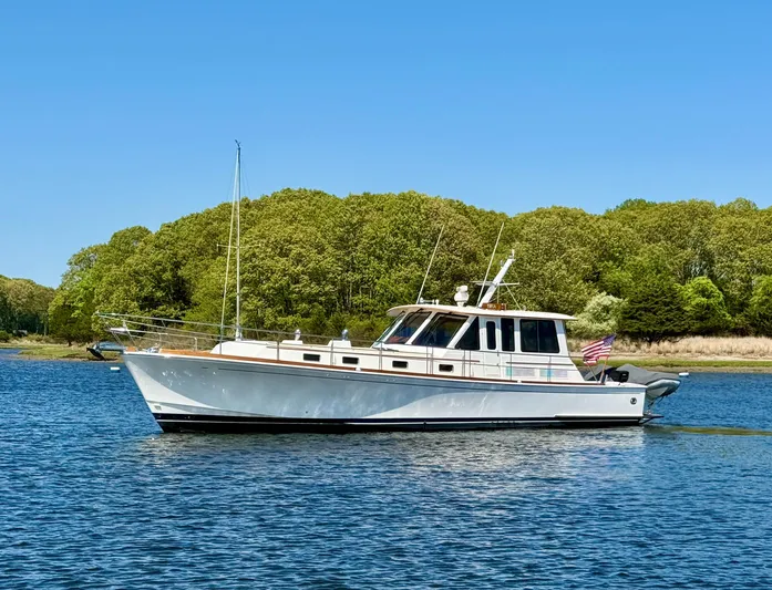 Bira Yacht Photos Pics 2006 Grand Banks 49 Eastbay SX yacht on calm water, surrounded by lush greenery.
