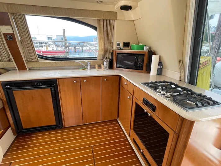 Queen Alexia Yacht Photos Pics 2005 Meridian 341 Sedan yacht kitchen with wood cabinets, stove, microwave, and scenic window view.