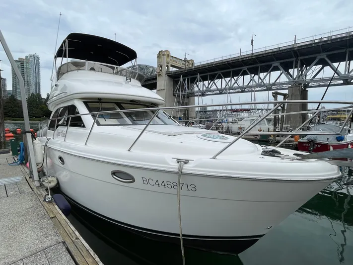 Queen Alexia Yacht Photos Pics 2005 Meridian 341 Sedan yacht docked near a bridge, urban skyline in background.