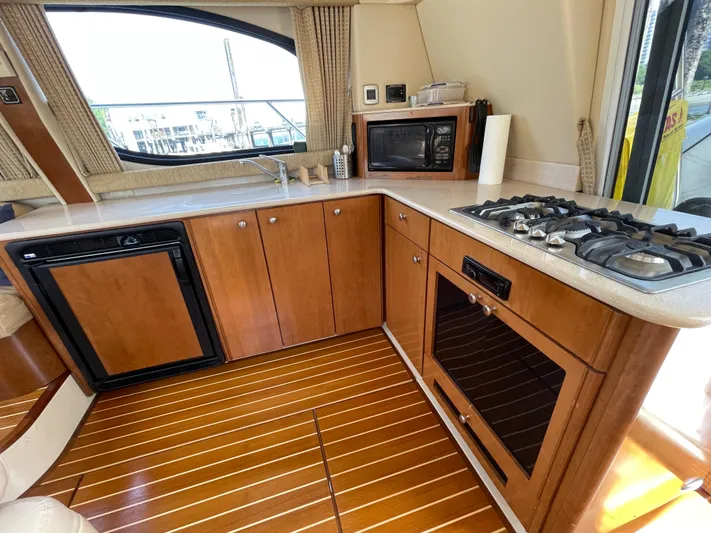 Queen Alexia Yacht Photos Pics 2005 Meridian 341 Sedan yacht kitchen with wood cabinetry, stove, microwave, and refrigerator.