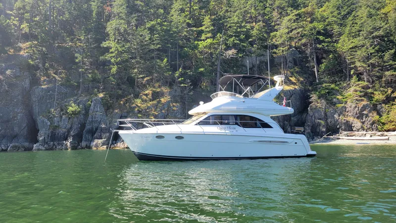 Queen Alexia Yacht Photos Pics 2005 Meridian 341 Sedan yacht anchored near a forested rocky shoreline.