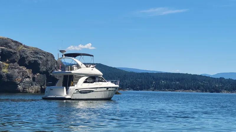 Queen Alexia Yacht Photos Pics 2005 Meridian 341 Sedan yacht on serene water with rocky cliffs and forested background.