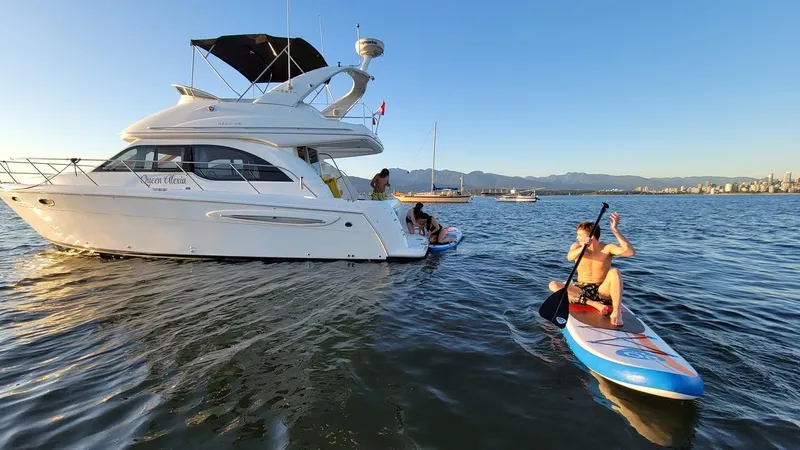 Queen Alexia Yacht Photos Pics 2005 Meridian 341 Sedan yacht with people paddleboarding nearby on a sunny day.