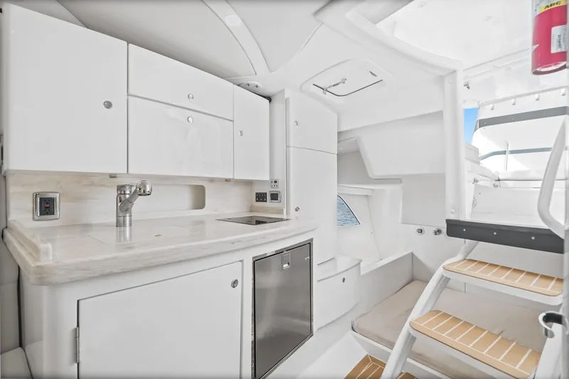  Yacht Photos Pics 2018 Intrepid 407 Cuddy interior with modern kitchenette and seating area.