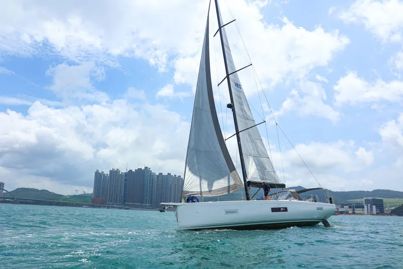  Yacht Photos Pics 2023 Beneteau First 53 sailing near urban skyline under a partly cloudy sky.