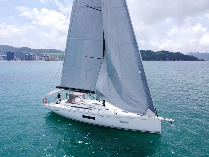  Yacht Photos Pics 2023 Beneteau First 53 sailing on calm waters with scenic coastal backdrop.