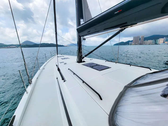  Yacht Photos Pics 2023 Beneteau First 53 yacht sailing on a calm sea with cityscape in the background.