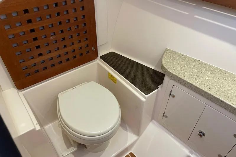  Yacht Photos Pics 2014 Grady-White Freedom 335 boat bathroom with toilet, wooden panel, and storage cabinet.