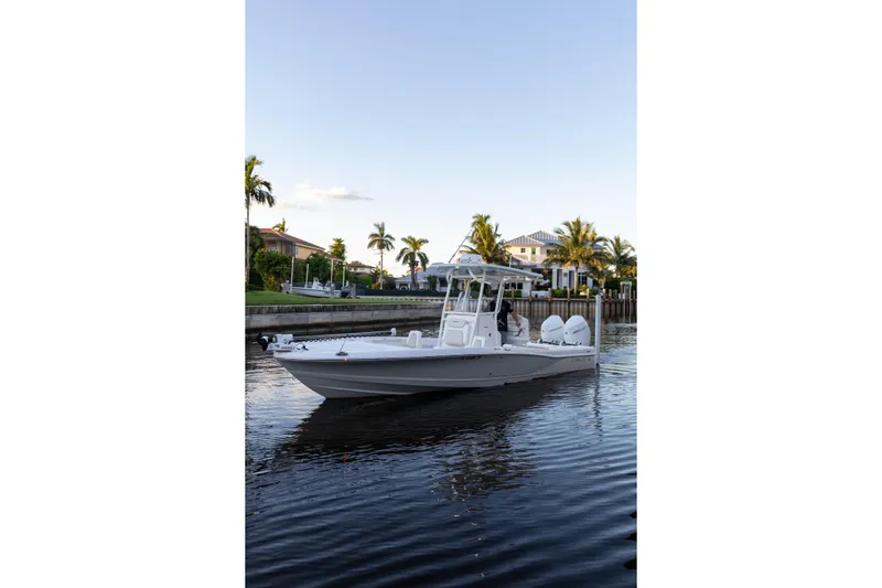  Yacht Photos Pics 2022 Caymas 28 HB Twin boat cruising on a calm waterway with palm trees in the background.