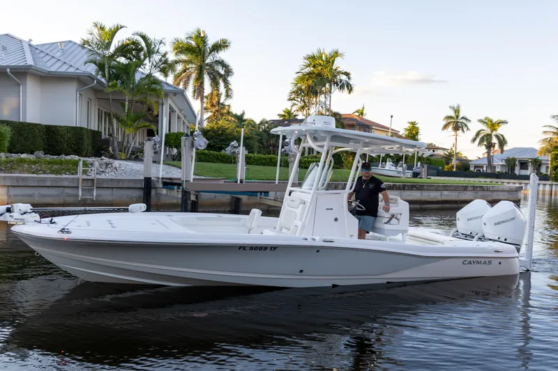  Yacht Photos Pics 2022 Caymas 28 HB Twin boat on a calm waterfront with palm trees.
