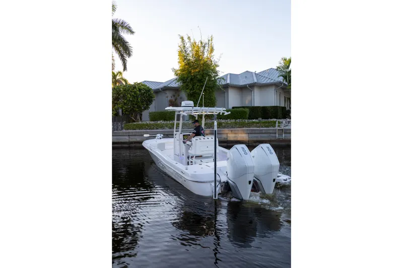  Yacht Photos Pics 2022 Caymas 28 HB Twin boat cruising on a calm waterway near residential area.