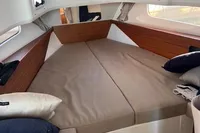 Cozy cabin interior of 2022 Nimbus T11 boat with comfortable bedding and wooden accents.