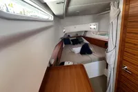Luxurious cabin interior of 2022 Nimbus T11 yacht with cozy bedding and wooden accents.