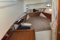 Cozy cabin interior of 2022 Nimbus T11 boat with comfortable bedding and wooden accents.