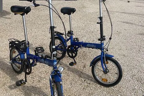 Seafox 1 Yacht Photos Pics Two blue folding bicycles on a gravel surface, featuring compact design and portability.
