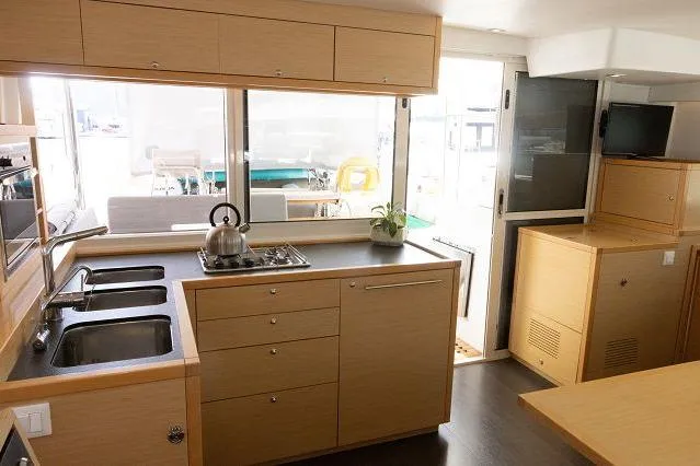 Seafox 1 Yacht Photos Pics Modern kitchen interior of 2015 Lagoon 400 S2 catamaran with wooden cabinetry and appliances.