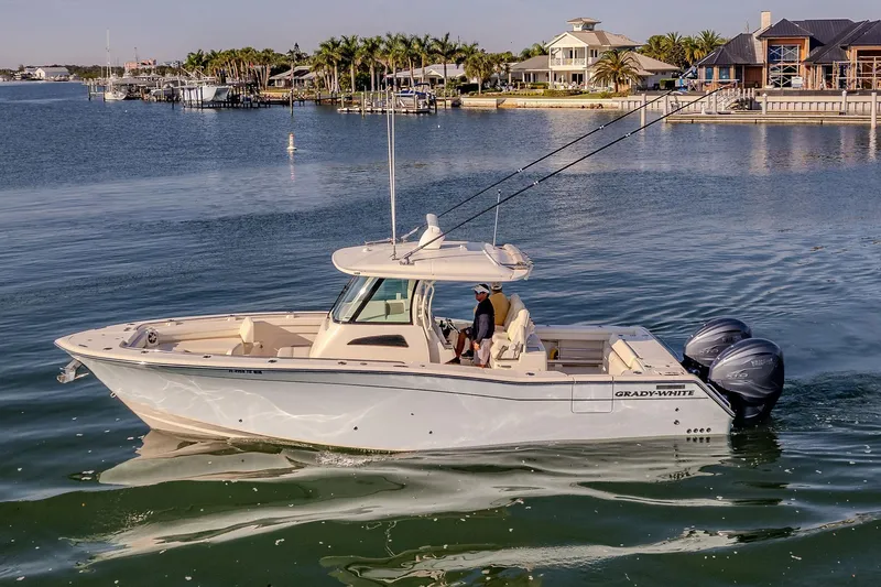  Yacht Photos Pics 2022 Grady-White Canyon 336 boat cruising on a serene waterfront with luxury homes.