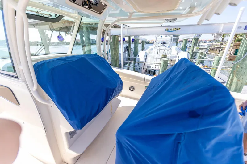  Yacht Photos Pics 2022 Grady-White Canyon 336 boat interior with blue-covered seats at a marina.