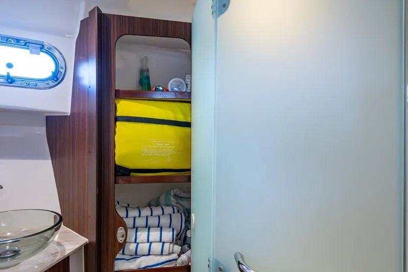  Yacht Photos Pics 2022 Pursuit OS 355 Offshore bathroom with glass sink, storage shelves, and porthole window.