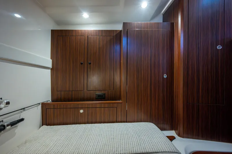  Yacht Photos Pics 2022 Pursuit OS 355 Offshore cabin interior with wood paneling and bed.