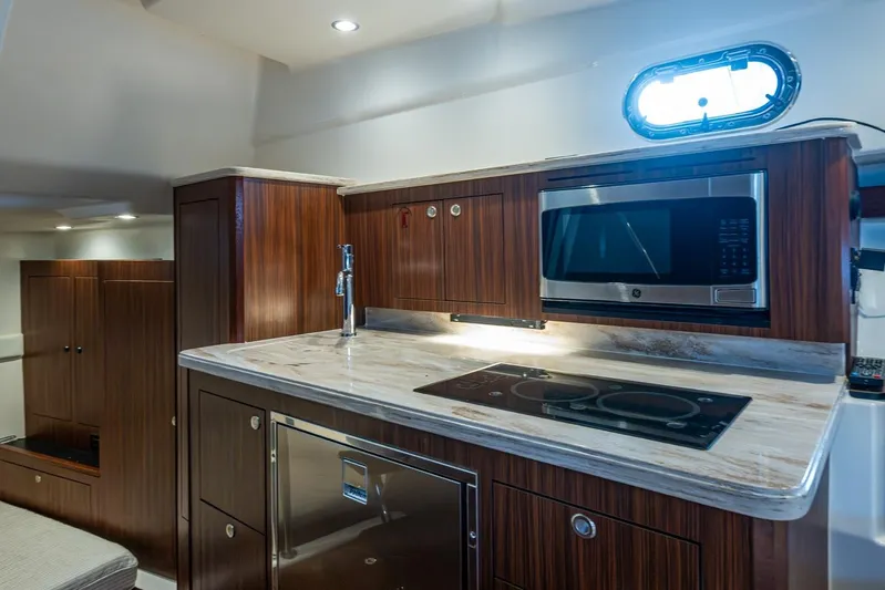  Yacht Photos Pics Luxurious 2022 Pursuit OS 355 Offshore yacht kitchen with modern appliances and elegant wood cabinetry.