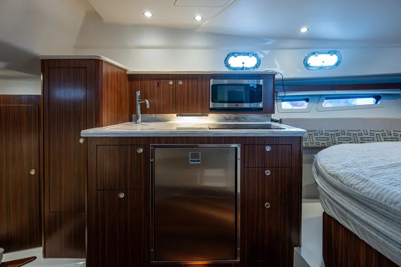  Yacht Photos Pics Luxurious 2022 Pursuit OS 355 Offshore yacht interior with modern kitchenette and wood finish.