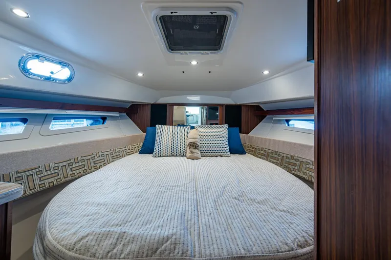  Yacht Photos Pics Luxurious cabin interior of 2022 Pursuit OS 355 Offshore with cozy bedding and elegant design.