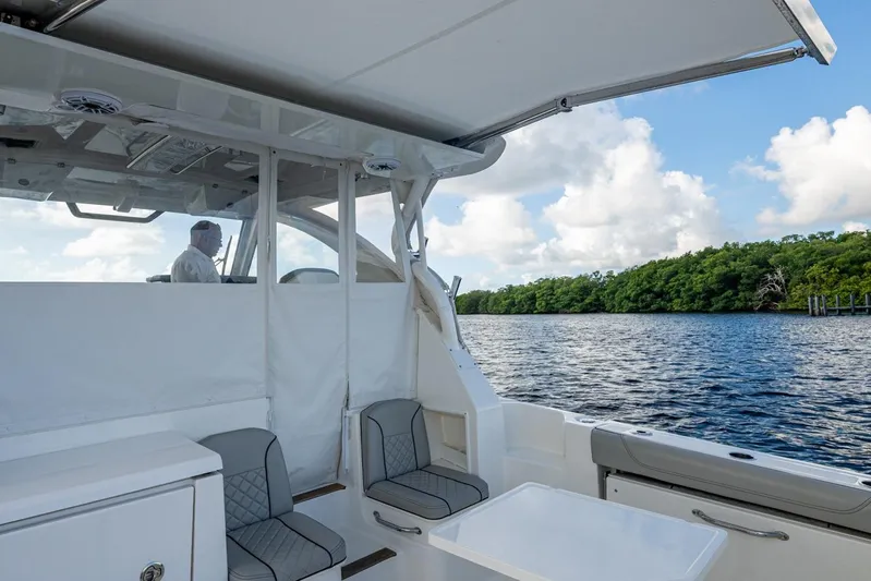  Yacht Photos Pics 2022 Pursuit OS 355 Offshore boat interior with seating, table, and scenic water view.
